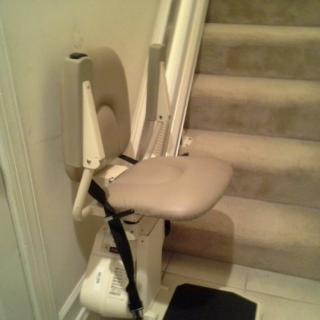 A stairlift installed beside a staircase, designed to assist individuals with mobility challenges.