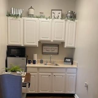A cozy kitchenette with white cabinets, a mini fridge, and decorative elements.