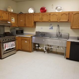 A spacious kitchen with wooden cabinets and industrial sink.