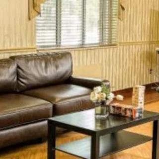 A cozy living room with a brown leather sofa and a black coffee table, adorned with flowers.