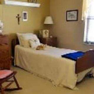A cozy bedroom with a single bed, lamp, and wall decorations.