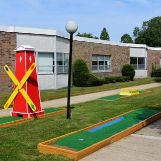 A vibrant mini golf course featuring a decorative windmill and neatly maintained greens.