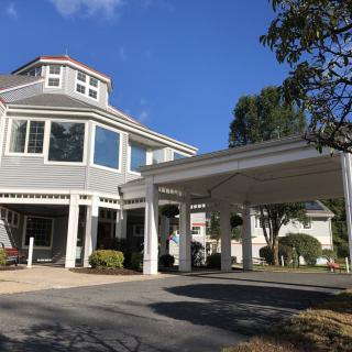 A residential building with a large covered driveway and surrounding trees.