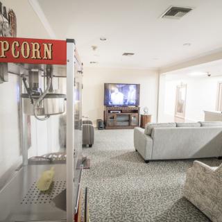 A cozy home theater setup with a popcorn machine and comfortable seating facing a large television.