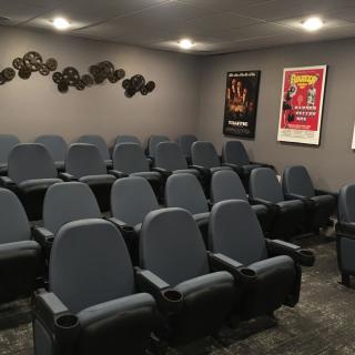 A cozy home theater with multiple rows of seats and movie posters on the walls.