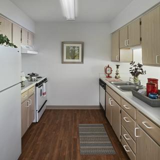 A modern kitchen with wooden cabinets, a stove, and a refrigerator, featuring ample countertop space.