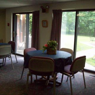 A cozy dining area with round tables and chairs, illuminated by natural light from large windows.