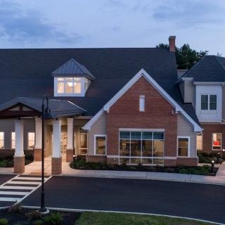 A well-lit brick house with a sloped roof in the evening.