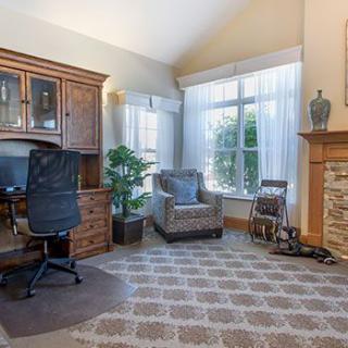 A cozy home office with a large window, desk, and comfortable seating.