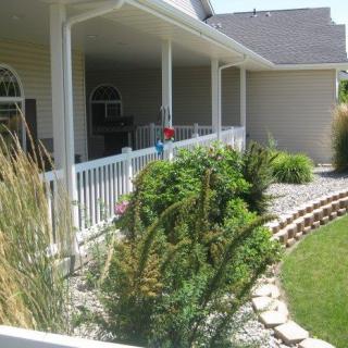 A beautifully landscaped garden with a porch and various plants.