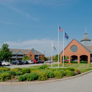 A sunny day showcasing a well-designed building with flags and landscaped greenery.