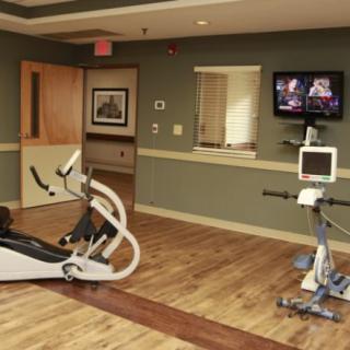 A fitness room equipped with stationary bikes and a television.