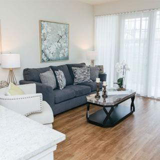 A modern living room with a dark gray sofa, light armchair, and a stylish coffee table, adorned with lamps and artwork.