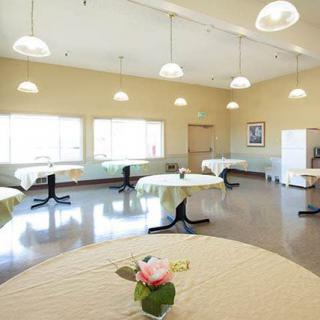 A bright dining room with tables decorated with rose centerpieces and plenty of natural light.