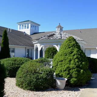 A well-maintained house surrounded by neatly trimmed shrubs and a clear blue sky.