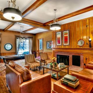 A cozy living room with wood paneling, leather furniture, a fireplace, and a pool table.