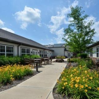 A beautifully landscaped courtyard with flowers and a pathway between buildings under a clear blue sky.