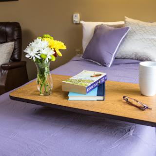 A cozy bedside table showcasing a vase of fresh flowers, a stack of books, and a cup of coffee.