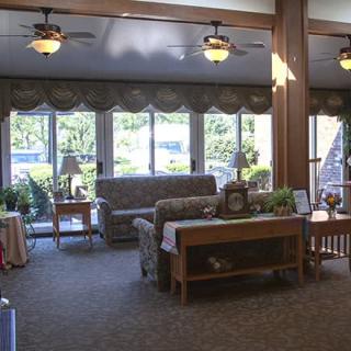 A cozy living room featuring a sofa, tables, and large windows letting in natural light.