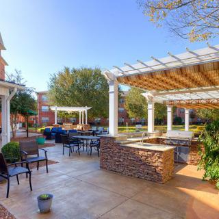 A spacious outdoor patio with seating and pergolas, surrounded by greenery.