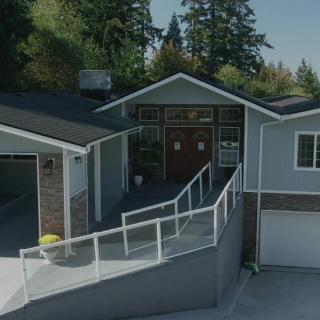 A modern residential house with a garage, surrounded by trees.