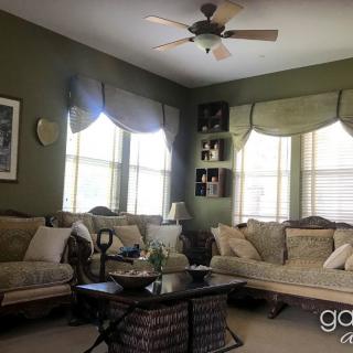A cozy living room with sofas, a coffee table, and large windows adorned with curtains.