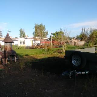 A peaceful view of a garden with a trailer and residential buildings in the background.