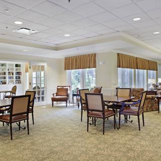 A spacious dining area with several tables and chairs, well-lit with natural light streaming through the large windows.