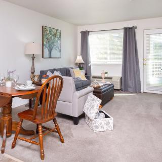 A cozy living room with a sofa, table, and chairs, featuring warm lighting and elegant decor.