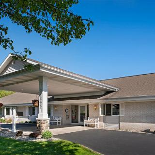 A modern building entrance with a covered driveway and surrounding trees.