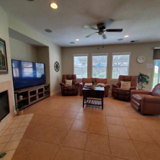 A cozy living room with a large TV, several sofas, and a coffee table on a tile floor.