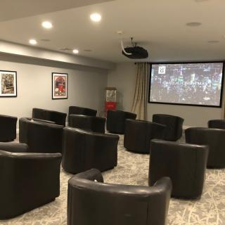 A cozy home theater setup with multiple chairs facing a large projector screen.