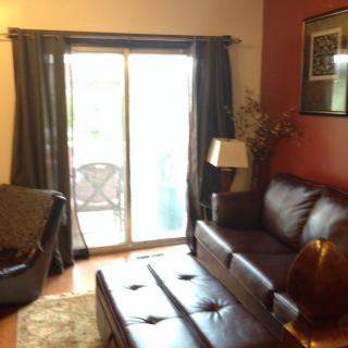 A cozy living room with a leather sofa, coffee table, and sliding glass doors leading to a patio.