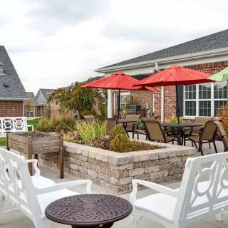 A cozy patio area with tables, chairs, and bright umbrellas under a cloudy sky.