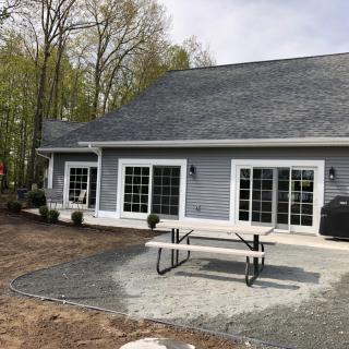A backyard view of a house with a patio table and chairs surrounded by trees.