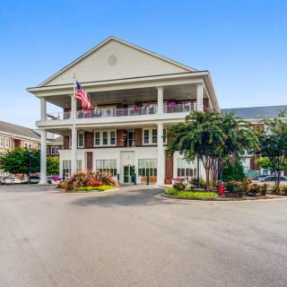 A large hotel building with a classic architectural style featuring palm trees and a national flag.