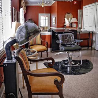 A cozy salon interior featuring vintage-style chairs and hairdryers against warm-colored walls.