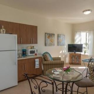 A cozy living area with a kitchenette, dining table, and television.
