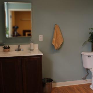 A simple bathroom with a vanity, mirror, towel, and toilet.