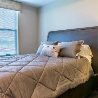 A cozy bedroom with a neatly made bed and pillows next to a window.