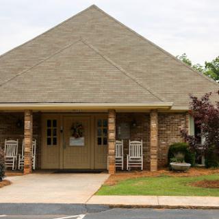 A cozy building with a welcoming entrance and outdoor seating surrounded by greenery.