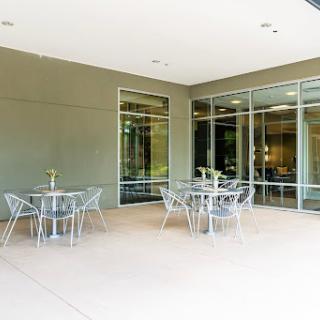 A modern outdoor patio area featuring glass walls and stylish furniture.