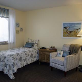 A cozy bedroom with a single bed, armchair, and decorative elements.