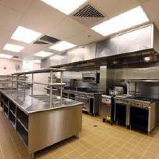 Industrial kitchen setup with stainless steel appliances and workstations.