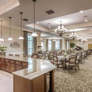 A spacious dining room with elegant chandeliers and neatly arranged tables and chairs.