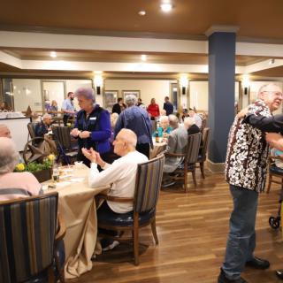 A lively social gathering of elderly individuals enjoying a dining event indoors.