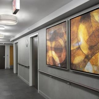 A modern hallway featuring abstract paintings and ceiling lights.