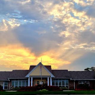 A serene sunset casts beautiful colors across the sky, illuminating the building in the foreground.