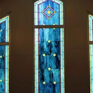A vibrant stained glass window featuring geometric patterns and a mix of blue tones.