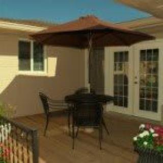 A cozy patio setup with a table, chairs, and an umbrella beside a house.